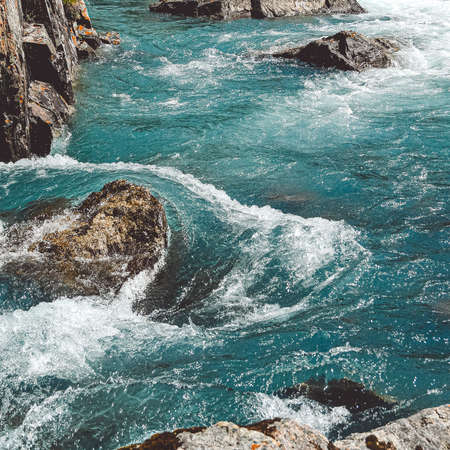 Rough river flow. The blue water of mountain river, the tide on sea with turquoise water and stone banksの写真素材