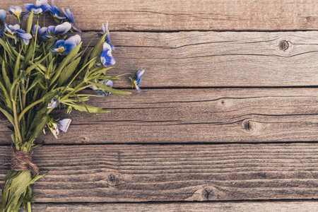 Bouquet of purple violets on wooden table. Old boards with garden flowers