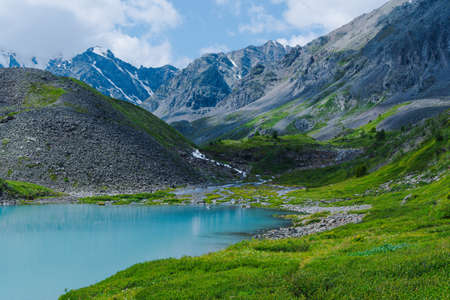 Turquoise lake among mountain peaks. High mountain river on summer day, hiking on rocks and stonesの写真素材