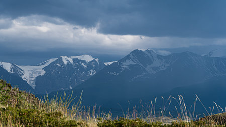 Ridge under the sky with clouds. Rocks with snow slopes, mountain landscape. Cross country tourist...