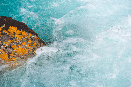 Mountain river with stone in blue water. Turquoise waves of sea tideの写真素材