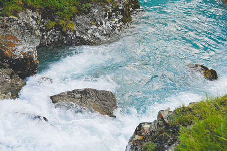 Rough river flow. The blue water of mountain river, the tide on sea with turquoise water and stone banksの写真素材