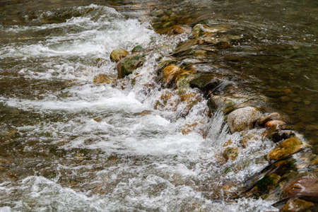 rocky bed of river, fast mountain stream with roiling stream. journey to nature in water valleyの写真素材