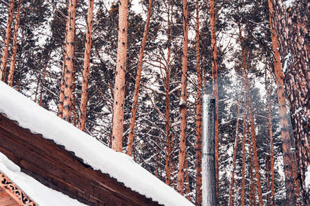 snow on roof of wooden house in winter forest, snowfall and cold snap, clearing house of snowの写真素材