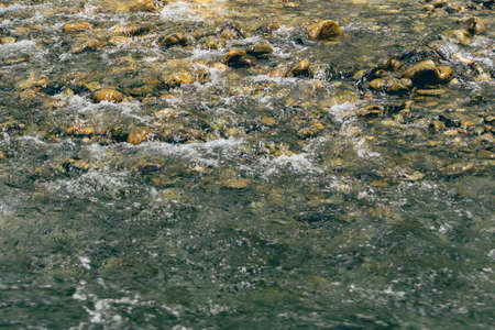 stream in stone bed, fast mountain river among rocks, water boils in eddies of currentの写真素材