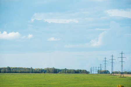 Farm field with power lines on horizon. Energy transportation