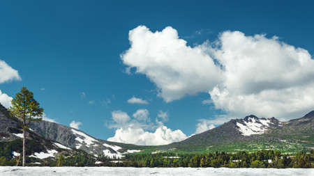 Mountain range under blue sky with cumulus clouds. Rocks and cliffs on the horizon on a sunny day. Travel through the highlands on foot.の写真素材