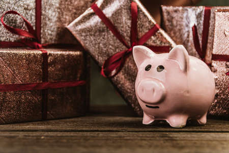 Piggy bank on background of gift boxes on birthday party. Concept saving money, thrift brings joy and shopping. Consolidation of funds, accumulation as protection against ruinの写真素材