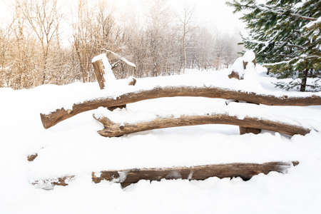 Wooden bench in winter city park is covered with snow. Sudden snowfall, changing weather and cooling. Need to clean territoryの写真素材