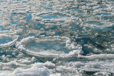 Round ice floes with fluffy edges in turquoise water of mountain river. Sunny frosty morning in surf...
