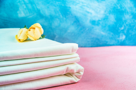 Fresh clean bed linen on pink bedspread on hotel. Stack of rolled fabric is being prepared for sewing.の写真素材