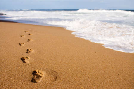 Human footprints leading away from the viewer into the seaの写真素材