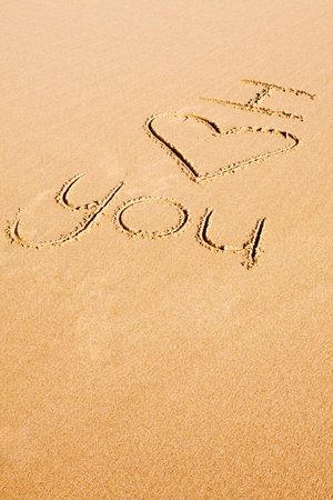 Words and a heart shape written in the beach sandの写真素材
