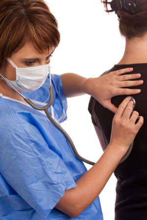 Young Caucasian female doctor listening to a patient's lungs using a stethoscopeの写真素材