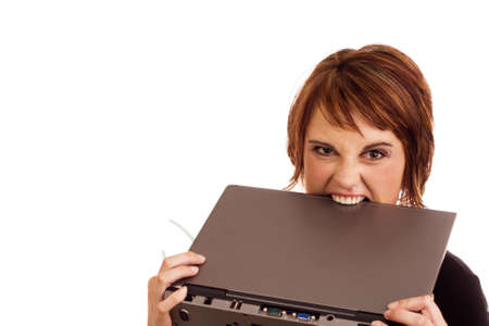 Frustrated Caucasian business woman holding her glasses and biting laptop in angerの写真素材