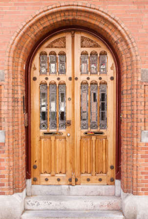 Closed antique wooden and glass door in red brick buildingの写真素材