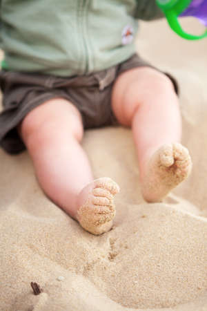 Curly toed baby feet covered with beach sandの写真素材