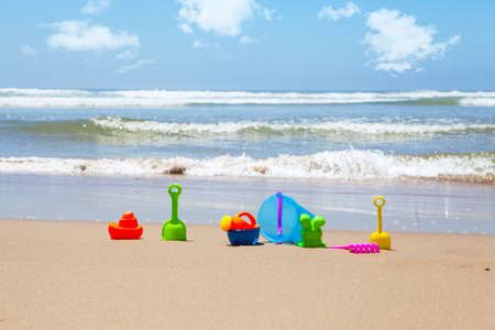 Plastic beach toys on beach with sea and clouds in backgroundの写真素材