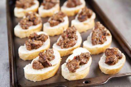 Cut french loaf on baking tray, loaded with peri-peri chicken liversの写真素材