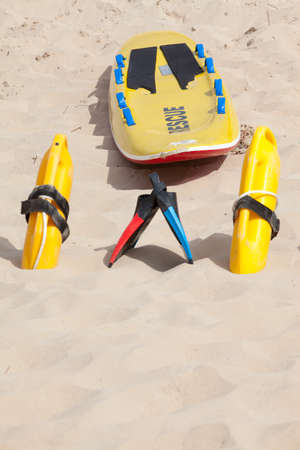 Lifesaving raft, floatation devices and swimming fins on beachの写真素材