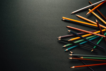 A bunch of colorful pencils showing from the right side of the from over a dark background