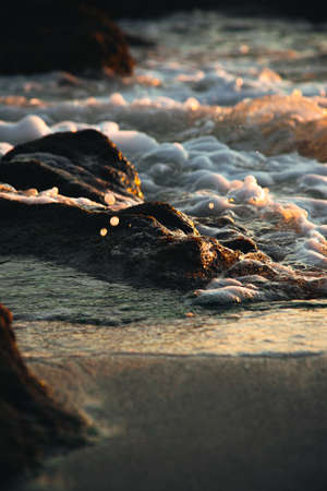Water making foam while crashing into the rocksの写真素材
