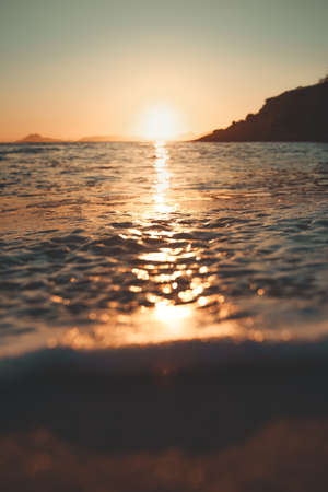 Sun reflecting over a tide in the beach during a sunsetの写真素材