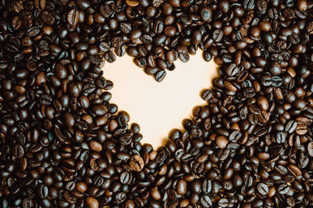A yellow heart inside a lot of coffee grainsの写真素材
