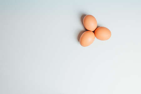 A white background with three eggs in a cornerの写真素材