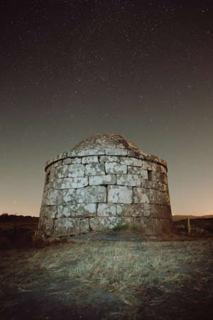 A rocky building during the night with a filled of stars backgroundの写真素材