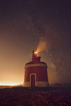 A lighthouse during the night with the sky with a lot of starsの写真素材
