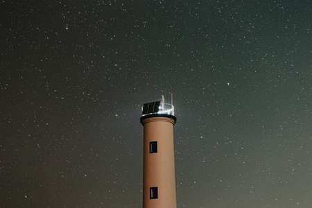 Close up of a white lighthouse with a sky filled of starsの写真素材