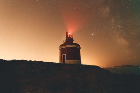 Horizontal shot of a lighthouse during the night with the sky with a lot of starsの写真素材