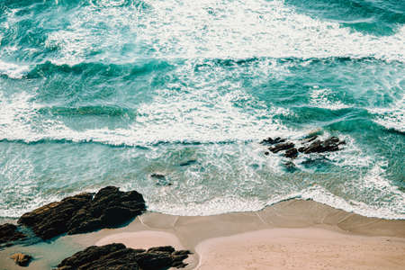 An horizontal aerial view of the waves over the sand of the beachの写真素材