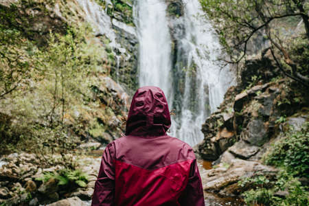 Young female hiker in front of a waterfallの写真素材