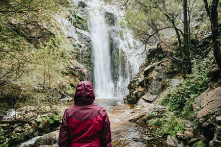A young female hiker in front of a waterfall with a lot of copy spaceの写真素材