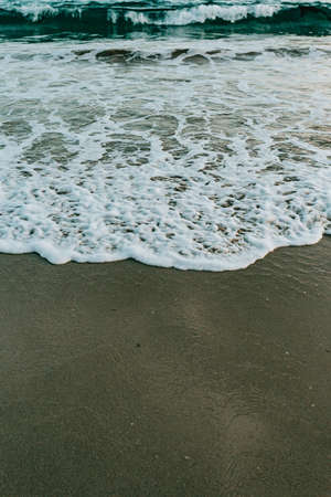 A single wave over the sand of the beachの写真素材