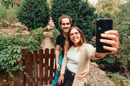 A young couple taking a selfie in front of a gorgeous rural houseの写真素材
