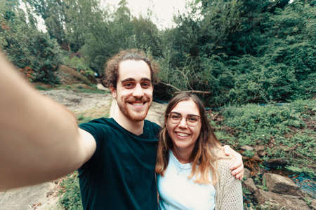 A young couple taking a selfie in the forest while smilingの写真素材