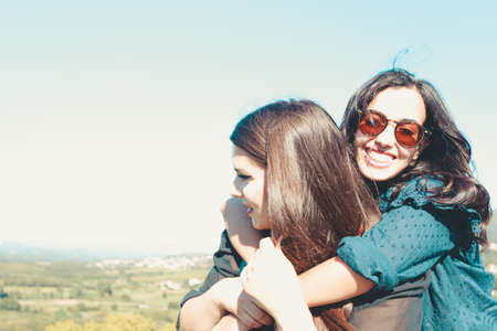 Two women hugging each other while one smiles to camera and uses sunglasses, with copy spaceの写真素材