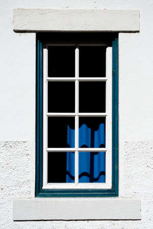 A front view of a white wall with a vintage window in it and a blue colorful interiorの写真素材