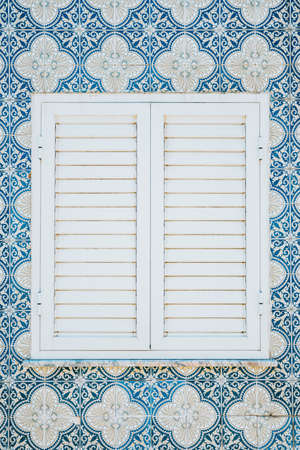 A minimalistic view of a white window surrounded by blue portuguese tilesの写真素材