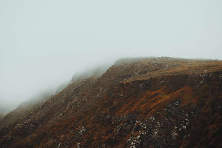 A close up of a massive red mountain in the north of europe during a foggy day with mist all over it with copy spaceの写真素材
