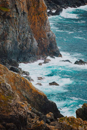 A wild close up of the bottom of the cliffs with the sea breaking against itの写真素材