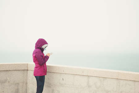 A woman checking her phone in a balcony and wearing hiking clothesの写真素材