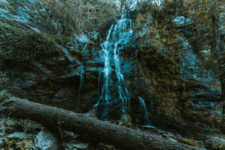 A massive waterfall in the middle of the natural forest with a broken truck in front during autumn