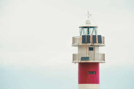 A minimalistic close up of a white and red lighthouse with a lot of copy spaceの写真素材