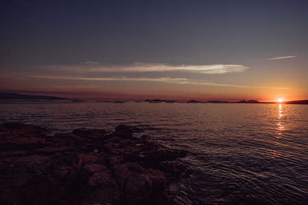 A dark pink sunset over the islands in the horizon from the spanish coastlineの写真素材