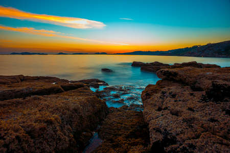 A long exposure sunset from the rocks on the coastline with a colorful horizonの写真素材