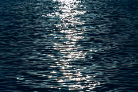 A blue colorful close up of the sea with the sun reflecting over itの写真素材